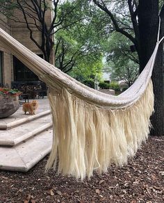 a large white hammock sitting in the middle of a yard next to a tree