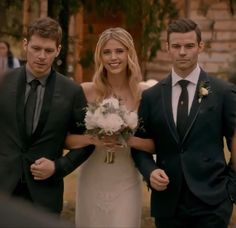 two men and a woman are walking down the aisle with their bouquets in hand