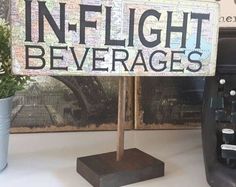 there is a sign that says in flight beverages next to a potted plant and typewriter