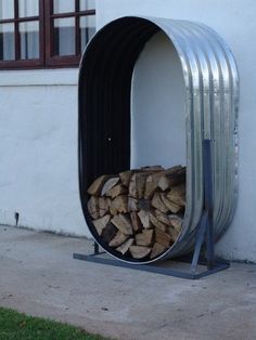 a pile of firewood sitting inside of a metal structure on the side of a building