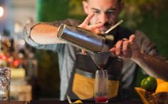 a man is making a drink at a bar with a shaker in his hand