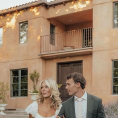 a man and woman are standing in front of a building