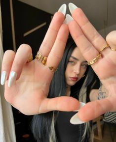 a woman is holding her hands up in the air with two gold rings on them