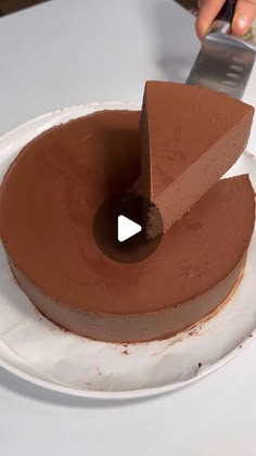 a person cutting into a chocolate cake with a knife