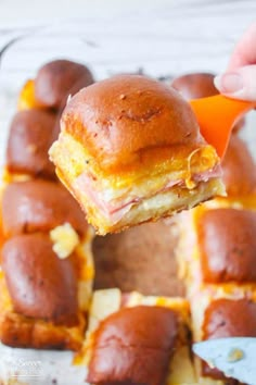 ham and cheese sliders being held up to the camera with a bite taken out