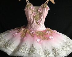 a pink and white tutu with gold sequins on the bottom, in front of a black background