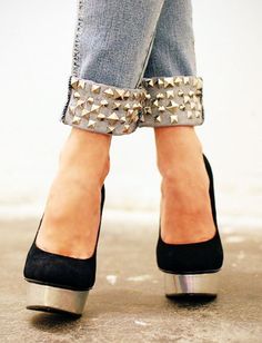 a woman's feet wearing black and silver shoes with studded heels on them