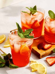 three glasses filled with watermelon and mint garnish next to strawberries