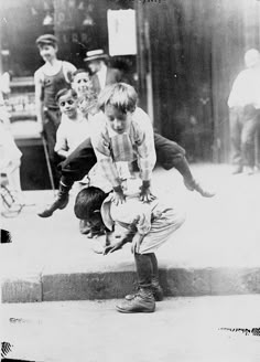 an old black and white photo of children playing on the steps in front of a building