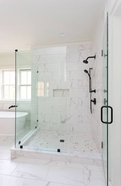 a white bathroom with marble flooring and glass shower doors, along with a walk - in tub