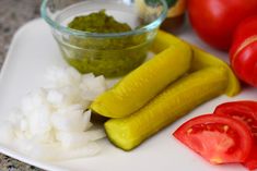 some vegetables are on a white plate with tomatoes and cucumbers next to them