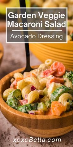 a wooden bowl filled with pasta salad next to a yellow bowl full of broccoli