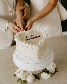 a bride and groom cutting into their wedding cake with the word love written on it