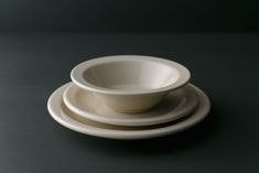 a stack of three white bowls sitting on top of each other in front of a black background