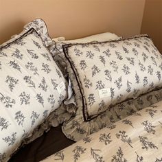 two pillows on top of each other with black and white floral designs in the middle