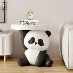 a panda bear table sitting on top of a wooden floor next to a white couch