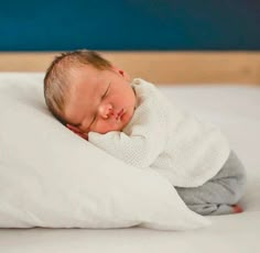 a baby sleeping on top of a white pillow