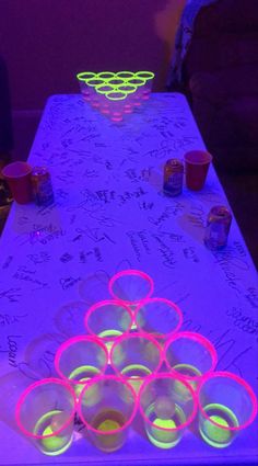 a long table with cups and neon lights on it