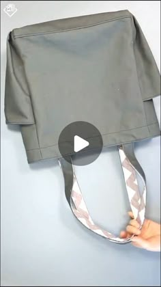 someone is holding the back of a gray bag with silver straps and an opening on it