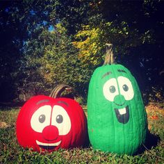 two pumpkins with faces painted on them sitting in the grass