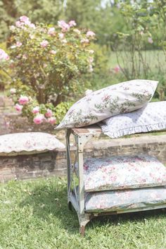 an old bench with pillows on it sitting in the grass