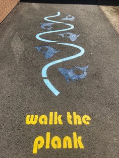 the sidewalk is painted with blue and yellow chalk on it, which says walk the plank