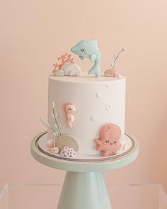 there is a white cake with sea animals on the top and under it, sitting on a glass stand