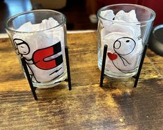 two glasses sitting on top of a wooden table covered in plastic wrap and stickers