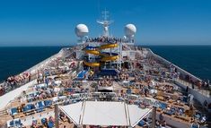 the top deck of a cruise ship with lots of people sitting on lounge chairs and water slides