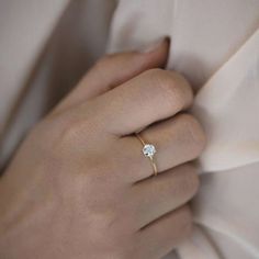 a woman's hand with a diamond ring on her left wrist, resting against a white shirt