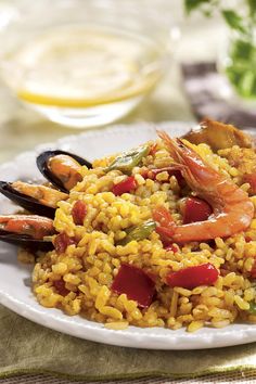 a white plate topped with rice covered in shrimp and mussels on top of a table