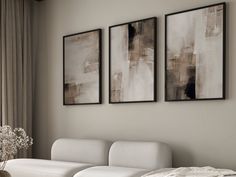 three paintings hang on the wall above a white couch and ottoman in a living room