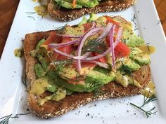 two slices of bread with avocado, tomato and onion on them