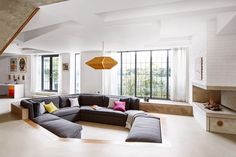 a large sectional couch in the middle of a living room with lots of windows and furniture