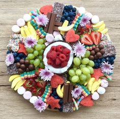 an arrangement of fruit and chocolates arranged in a circle on a wooden table top