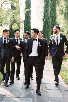 a group of men in suits walking down a sidewalk