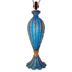 a blue and gold vase sitting on top of a white table next to a lamp