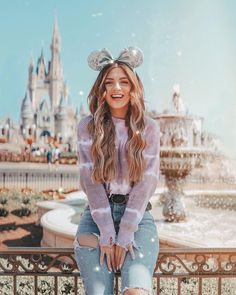 a woman sitting on a fence in front of a castle