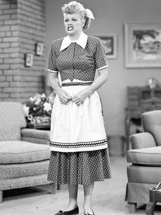 an old photo of a woman standing in a living room with her hands on her hips