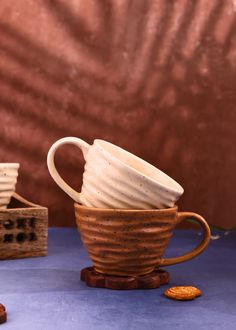 a stack of coffee cups sitting on top of a blue table next to a wooden box