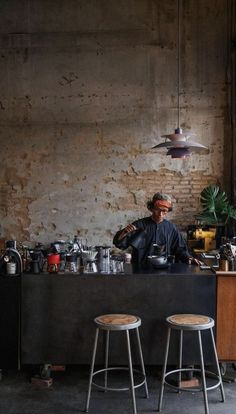 a man sitting at a bar with two stools in front of him and pots on the counter