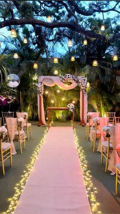 an outdoor wedding venue decorated with pink and white linens, lit up by fairy lights