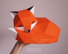 a hand holding an origami fox mask