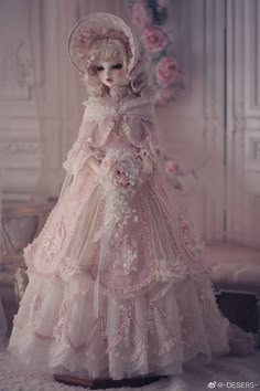 a doll in a pink dress and bonnet with flowers on the head is posed for a photo