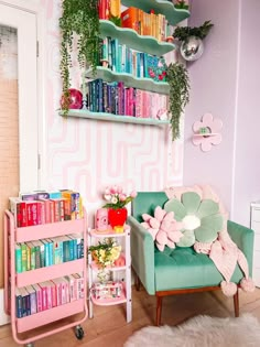 a pink and green room with bookshelves filled with books, flowers and plants