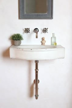 a white sink sitting under a bathroom mirror next to a wall mounted faucet