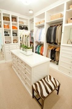 an organized closet with white cabinets and drawers