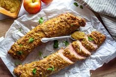 two meatloafs are sitting on wax paper next to some apples and bread