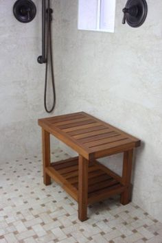 a wooden table sitting in the middle of a bathroom next to a shower head and hand shower