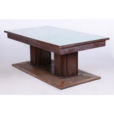 a wooden table sitting on top of a white floor next to a metal plate with a glass top